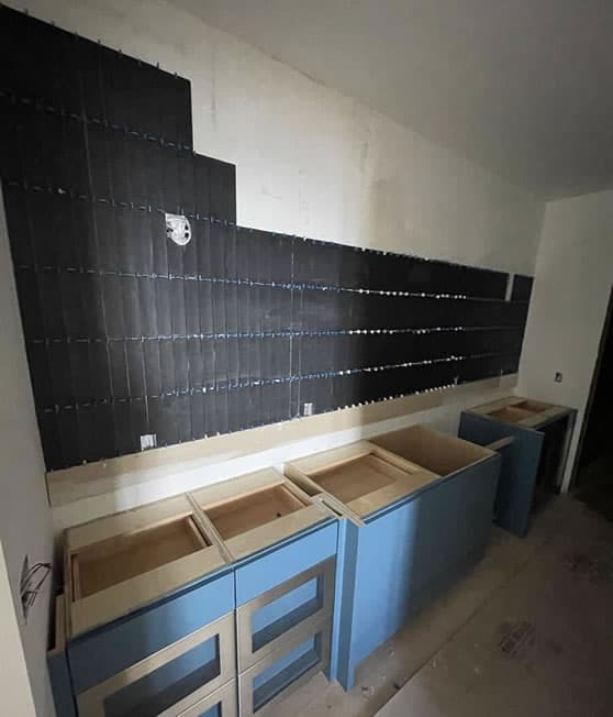Construction in process: rough blue kitchen cabinets with backsplash